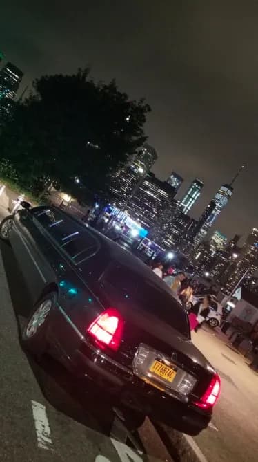 Black Lincoln stretch limousine at night against the Lower Manhattan skyline