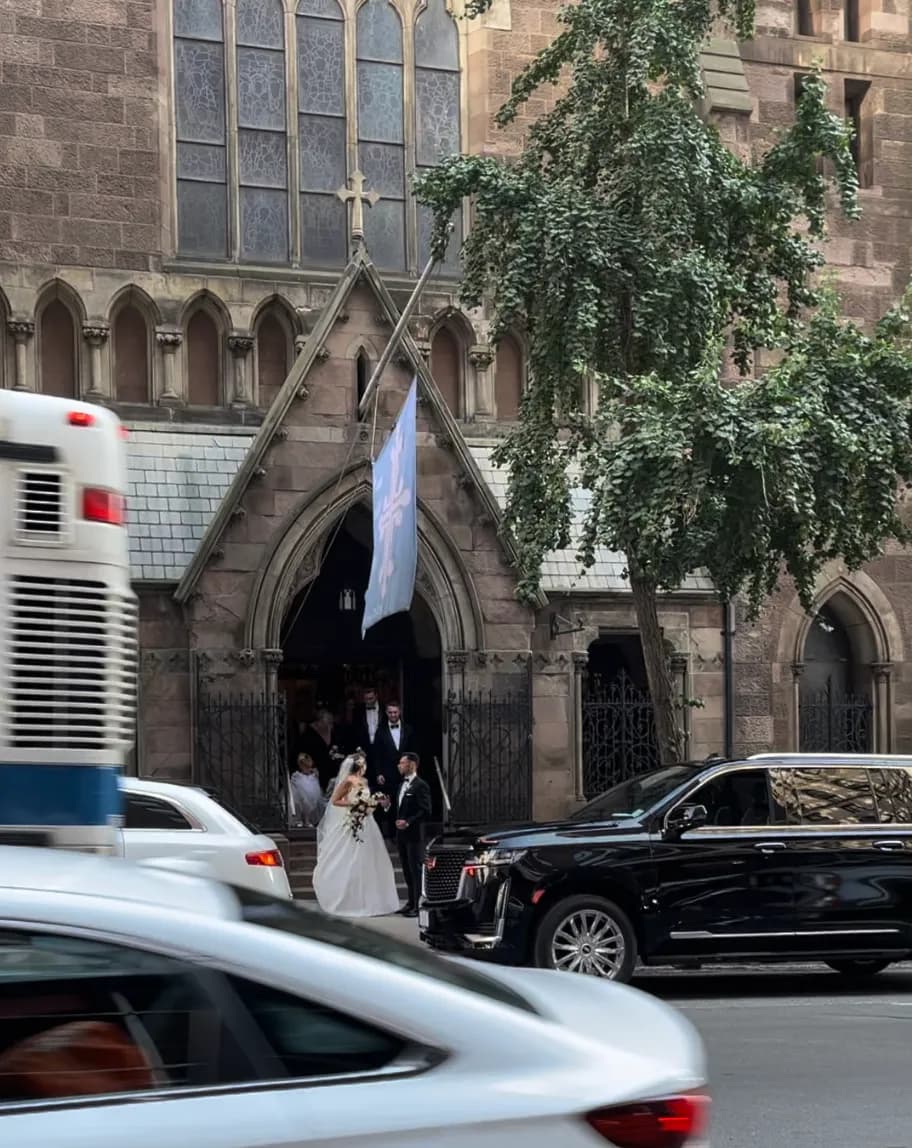 Bride and groom leaving the stone church with a black Escalade waiting