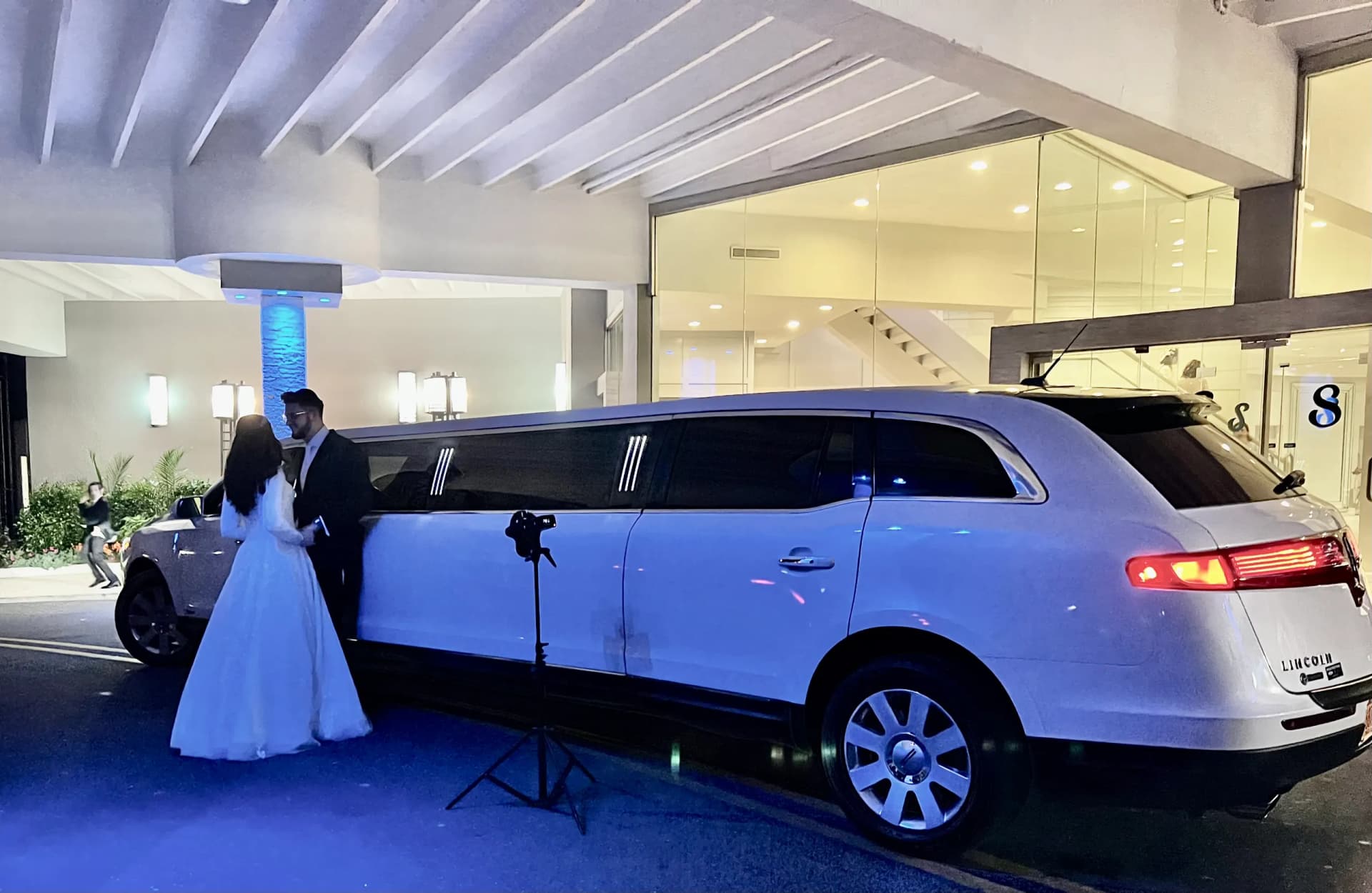 Bride and groom beside a white Lincoln MKT limousine at an evening reception
