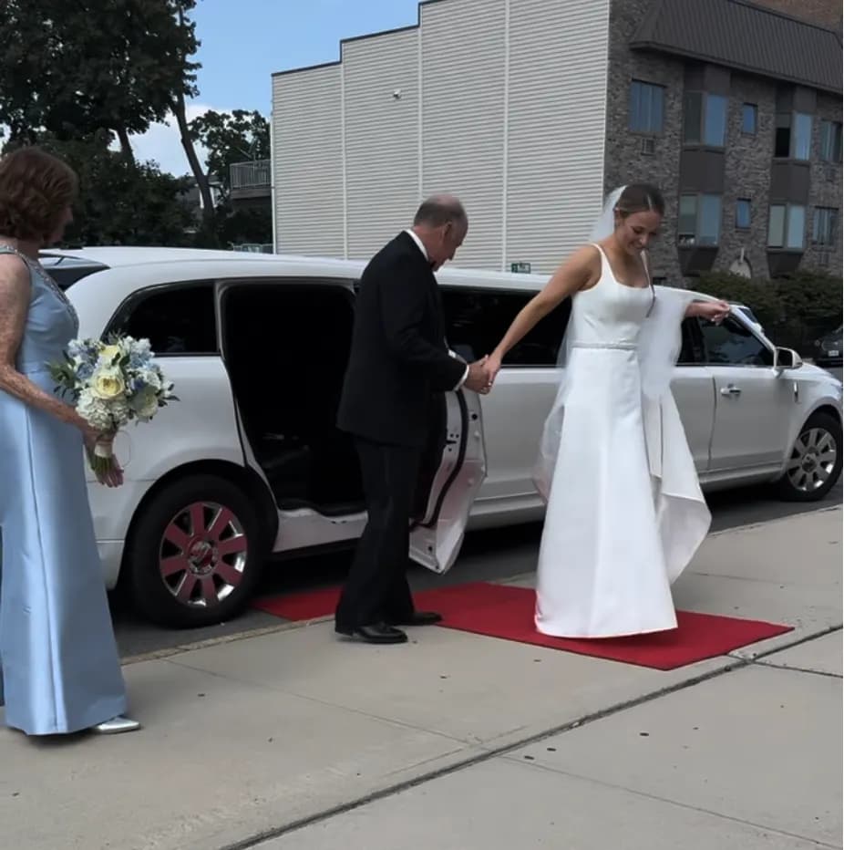 Bride stepping onto a red carpet from the white limousine