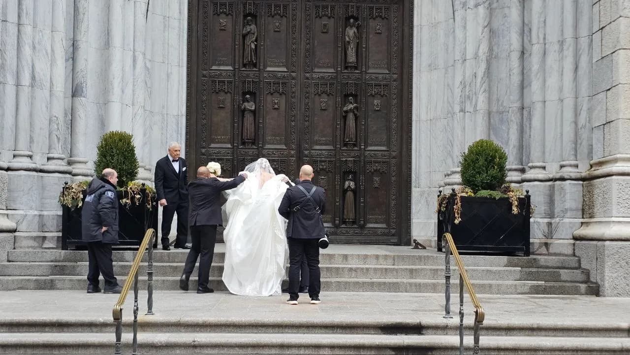 Attendants carrying the bride's veil up the steps of St. Patrick's Cathedral