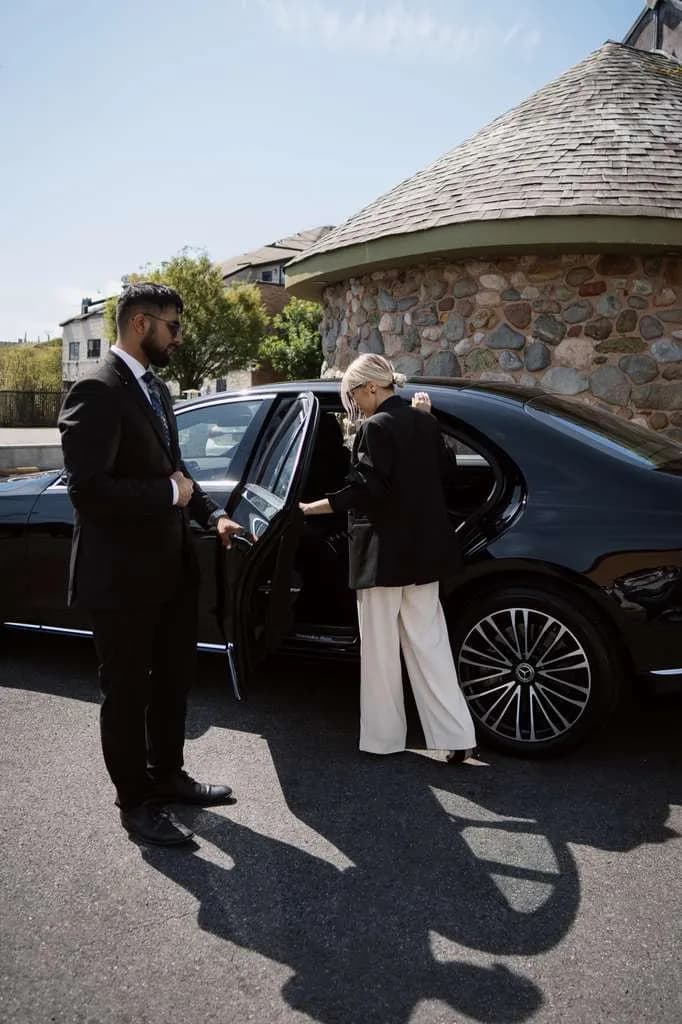 Chauffeur opening the Mercedes S-Class door for a guest at a stone winery building