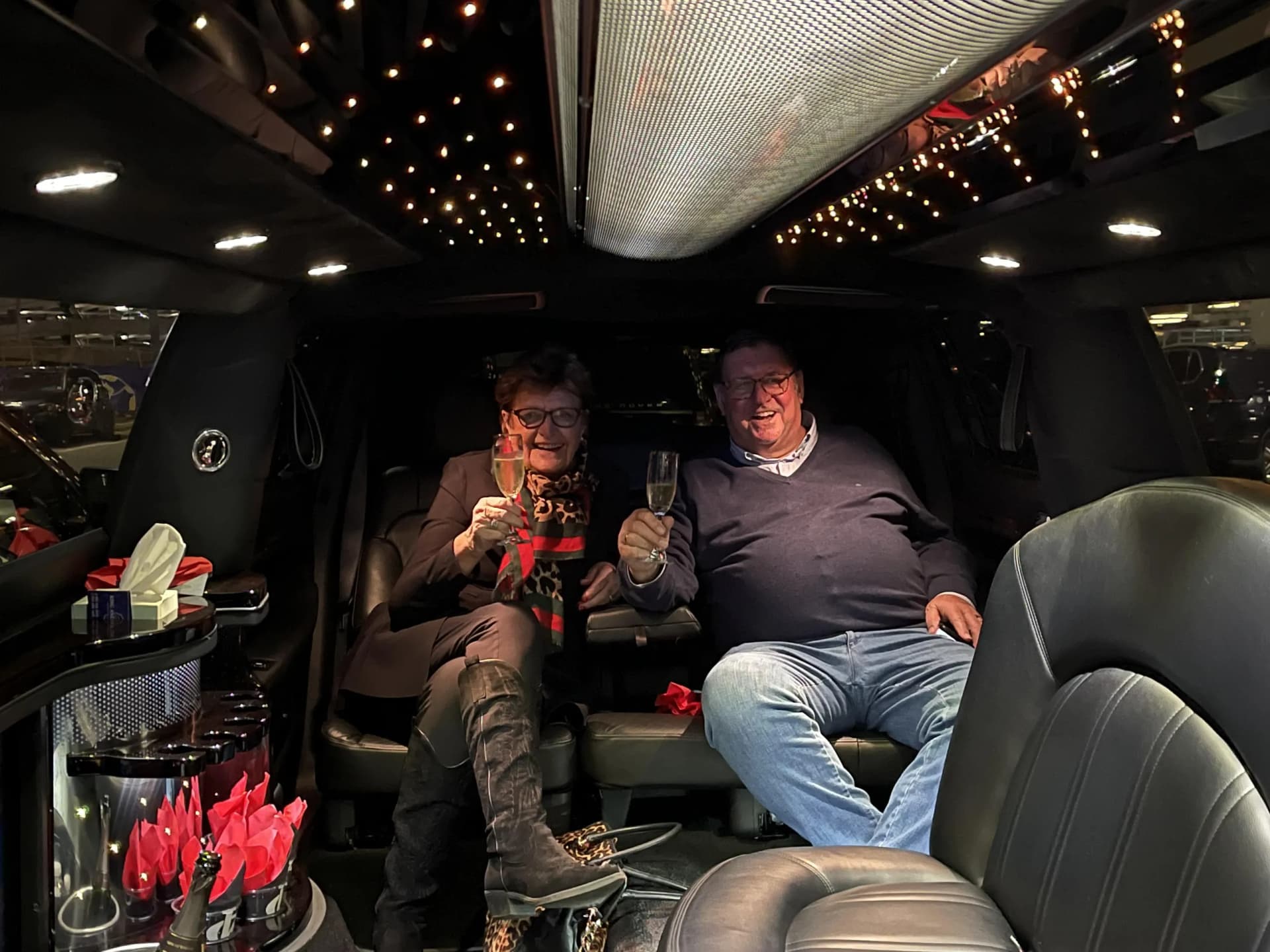 Couple toasting with champagne under the limo's starlight ceiling