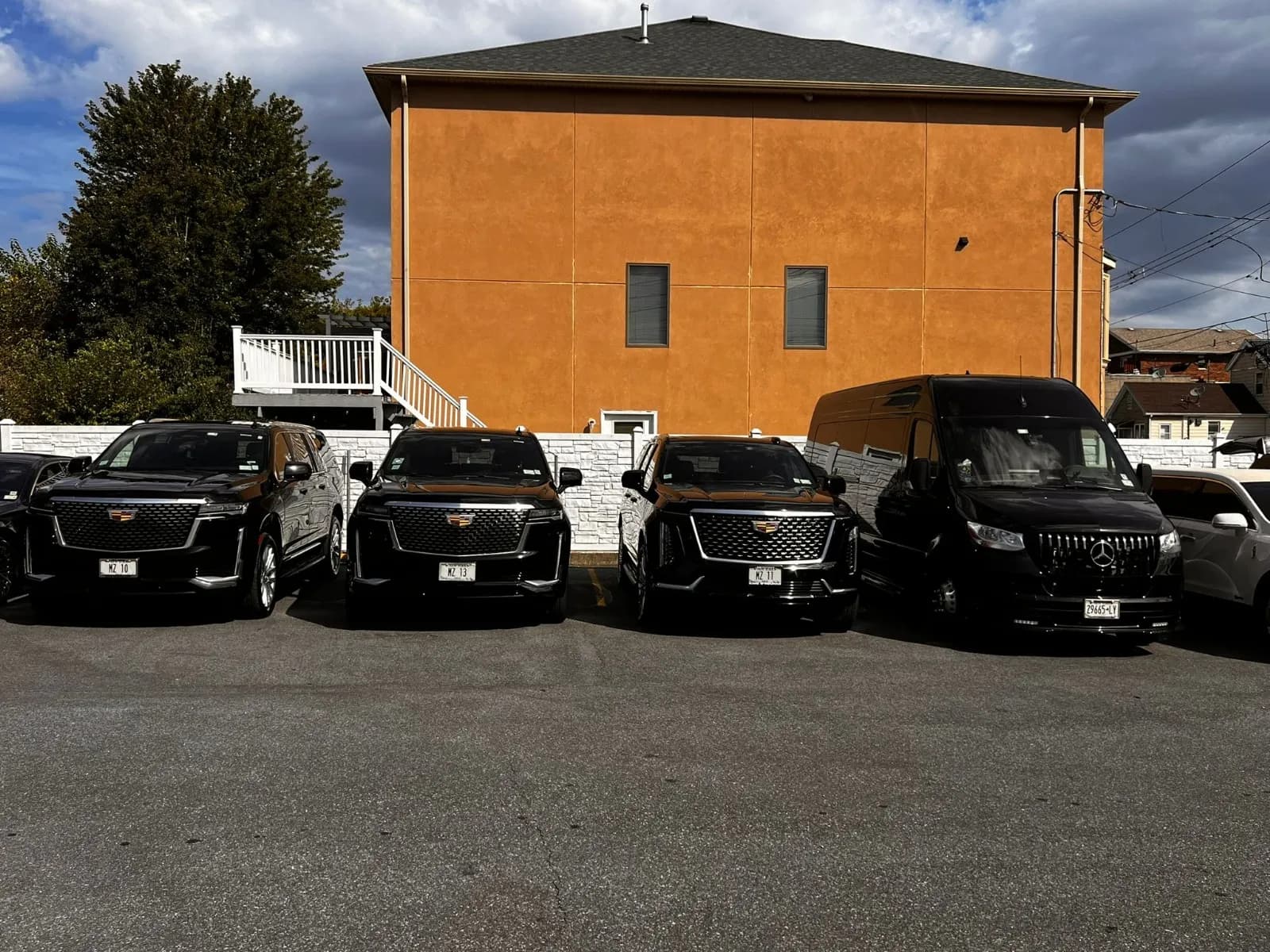Three Cadillac Escalades and a Mercedes Sprinter lined up in the yard