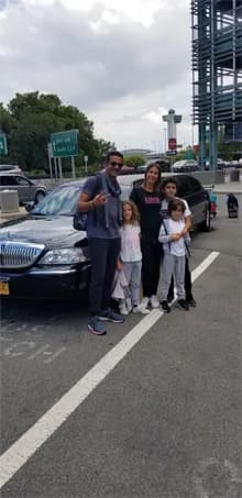 Family with kids beside a Lincoln limousine after landing at the airport
