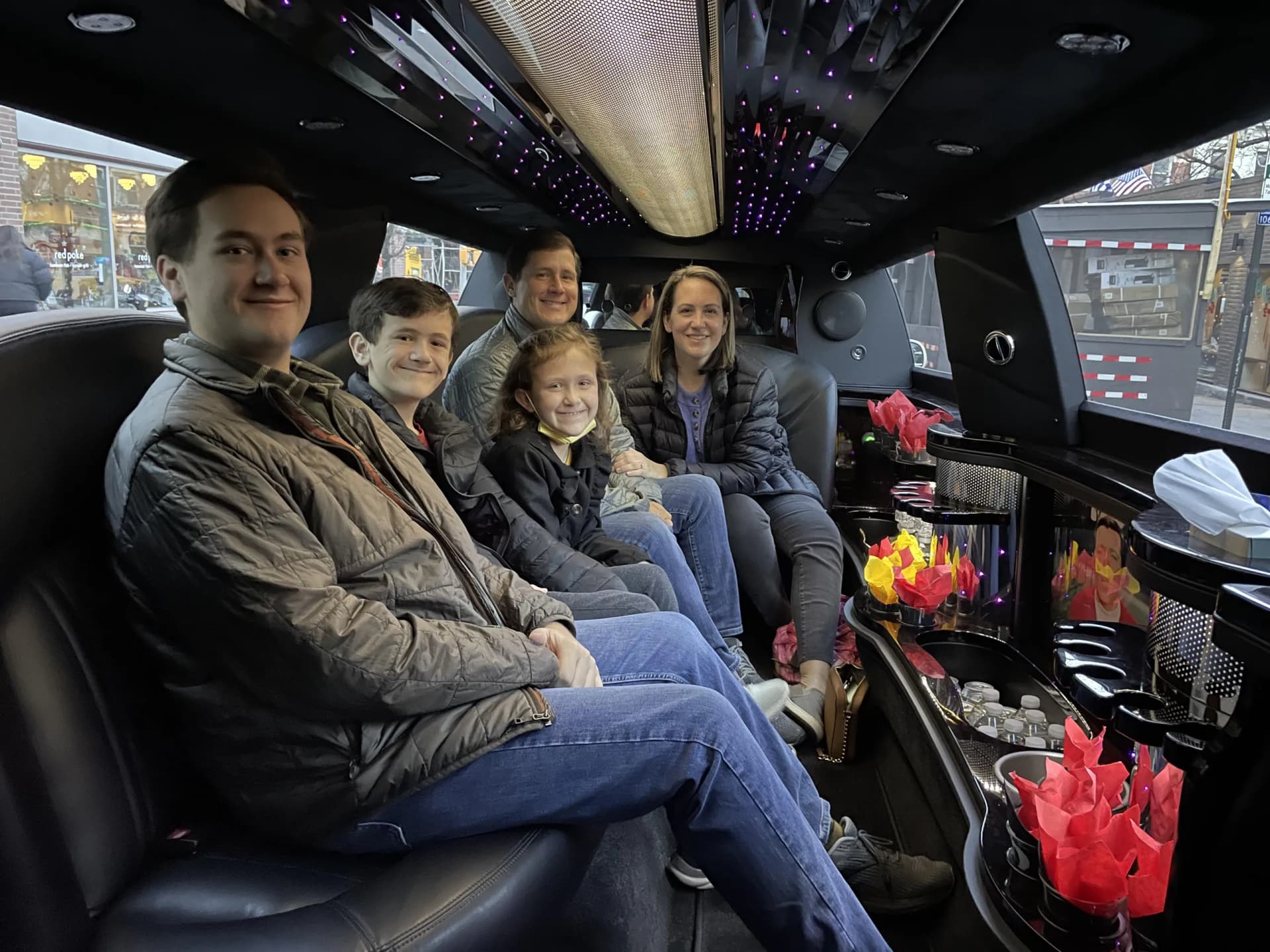 Family on a private tour inside a stretch limousine with a decorated bar