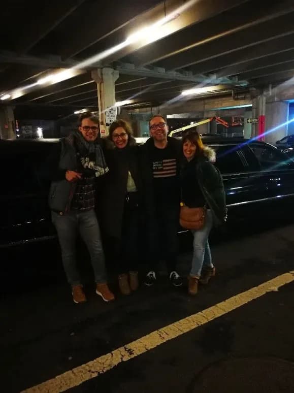 Four friends beside their black SUV in a parking garage after the show