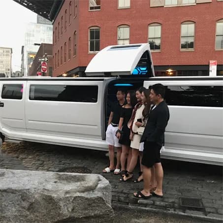 Friends boarding a white Hummer stretch limousine on a cobblestone street in Dumbo