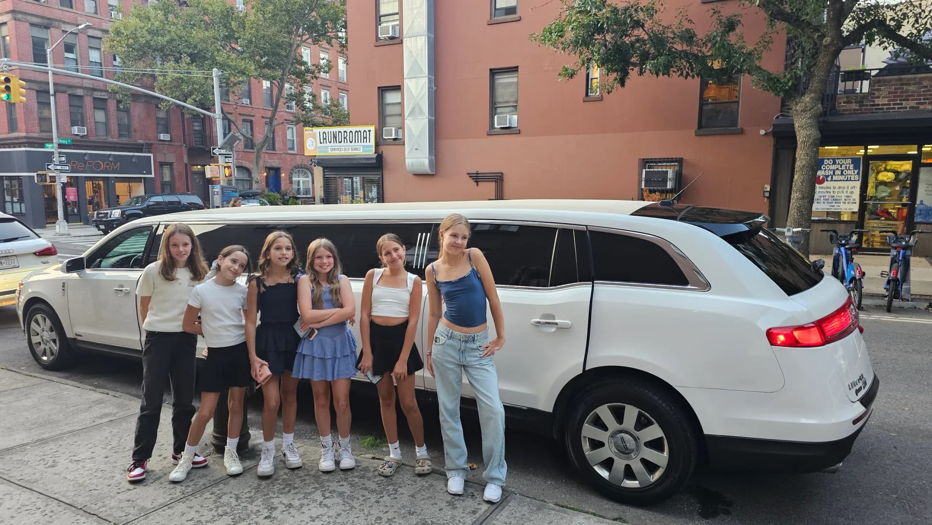 Girls lined up beside a white Lincoln stretch limousine for a birthday outing