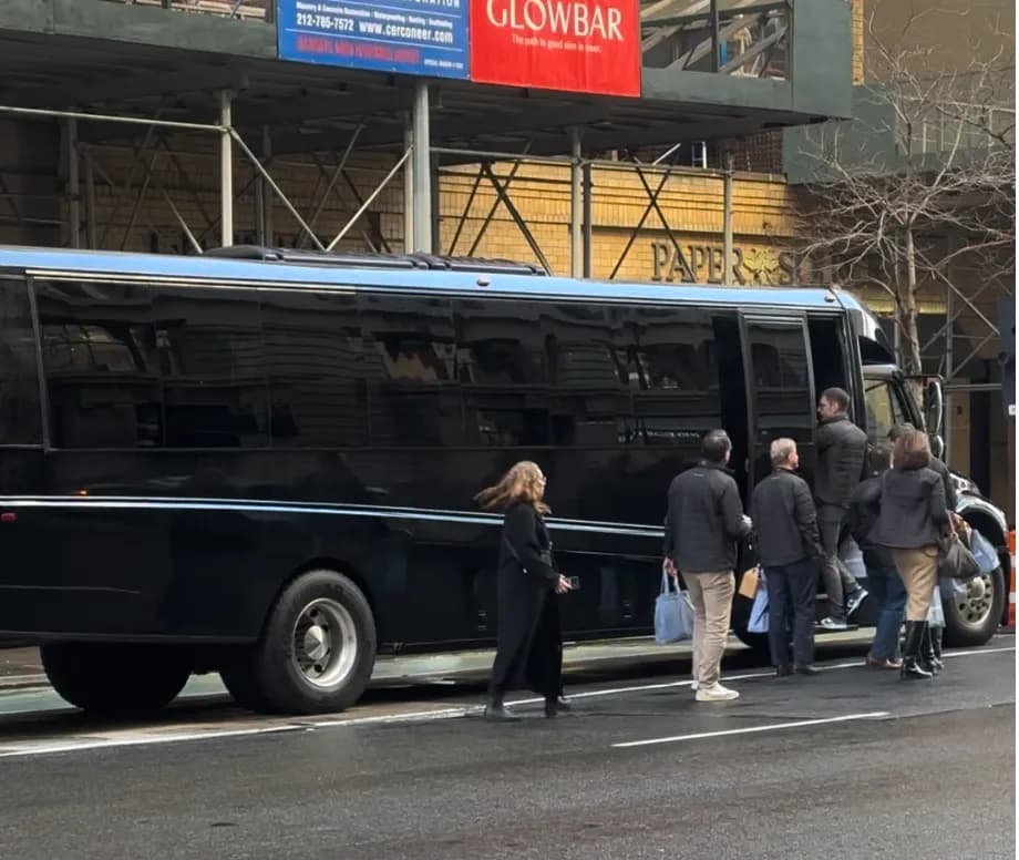 Guests with shopping bags boarding a black shuttle bus in Manhattan