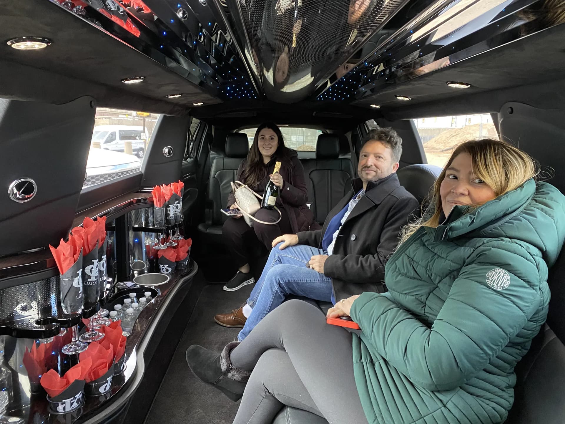 Three guests with champagne inside the limousine on a winter outing