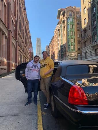 Two guests beside a black Lincoln stretch limousine before the game