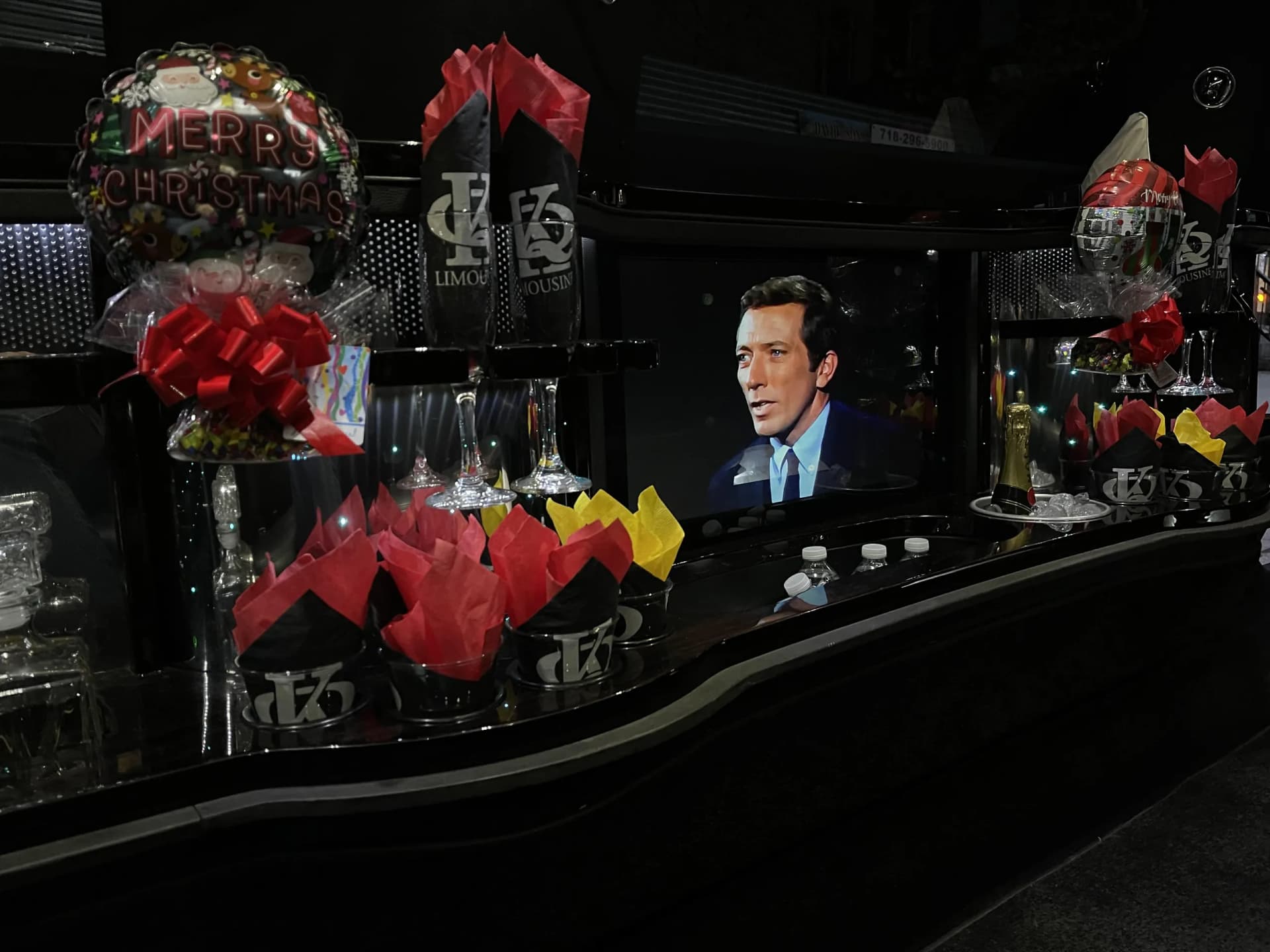 Limousine bar decorated for Christmas with balloons and holiday movies on TV