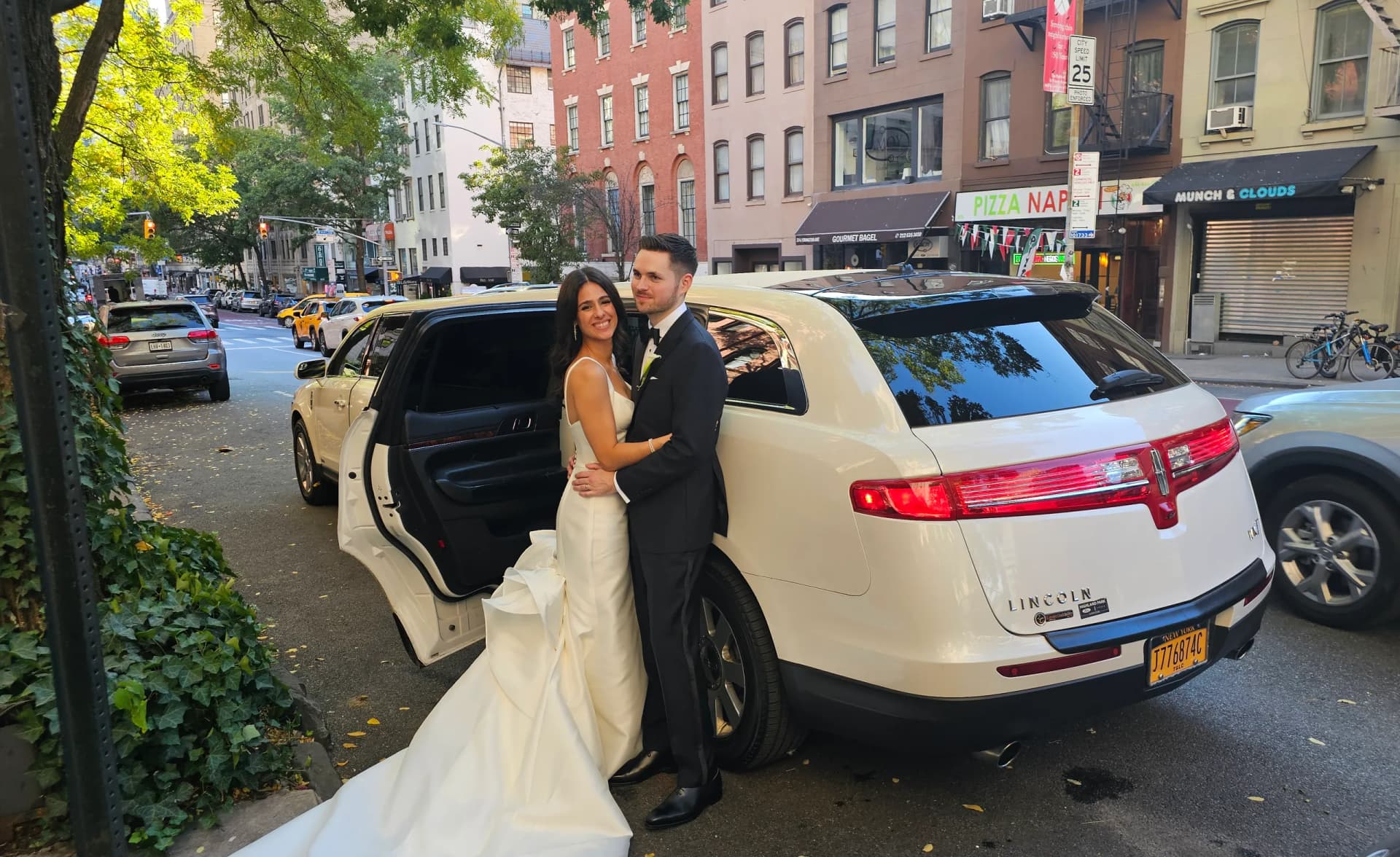 Newlyweds embracing beside their white limousine on a Manhattan street