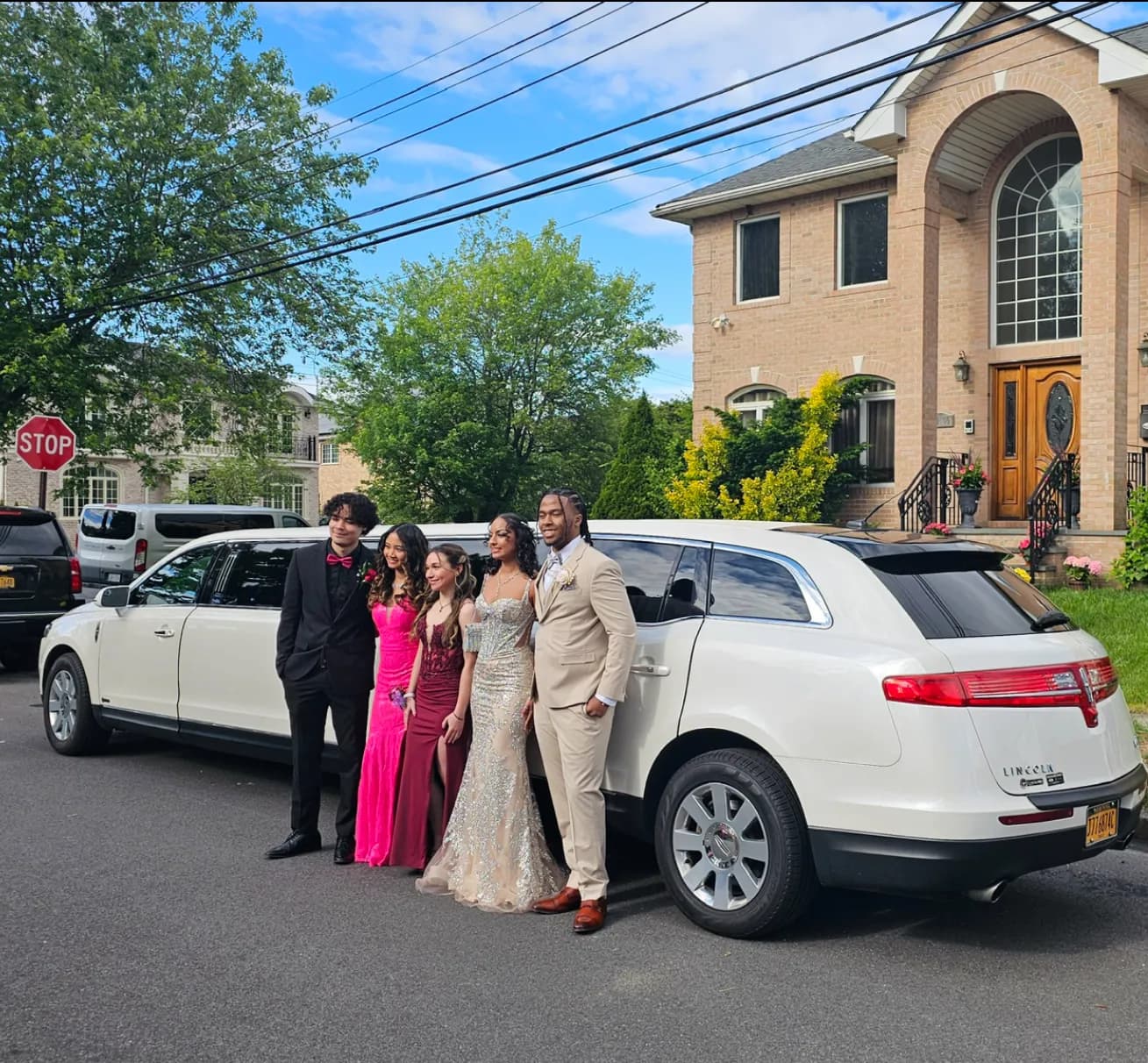 Prom group in gowns and suits beside a white Lincoln stretch limousine