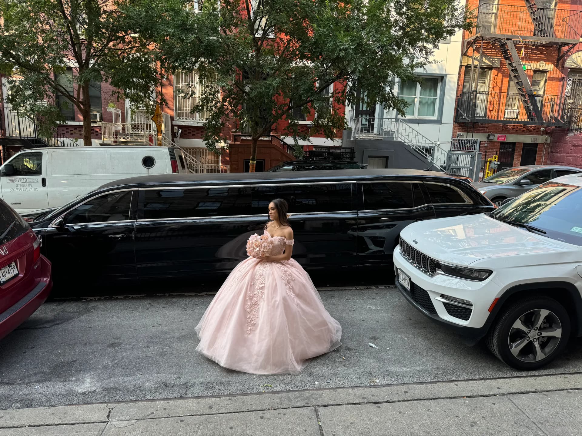 Quinceanera in a pink gown beside a black SUV stretch limousine