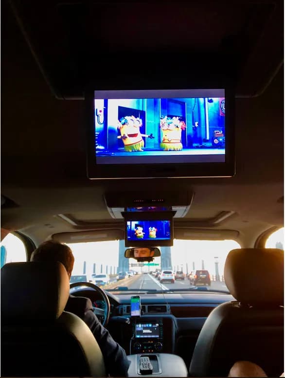 Rear entertainment screens playing a movie inside a luxury SUV