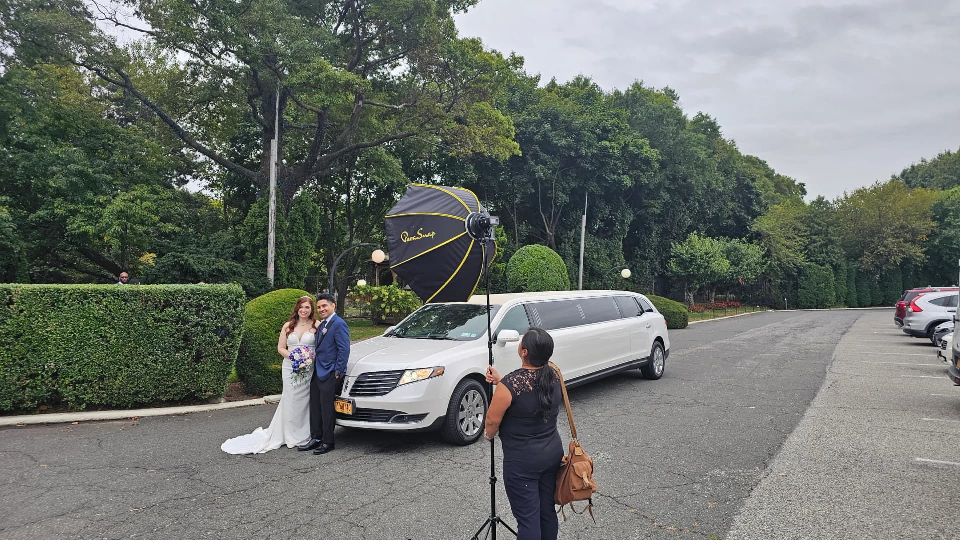Photographer shooting the couple with their white stretch limo in the park