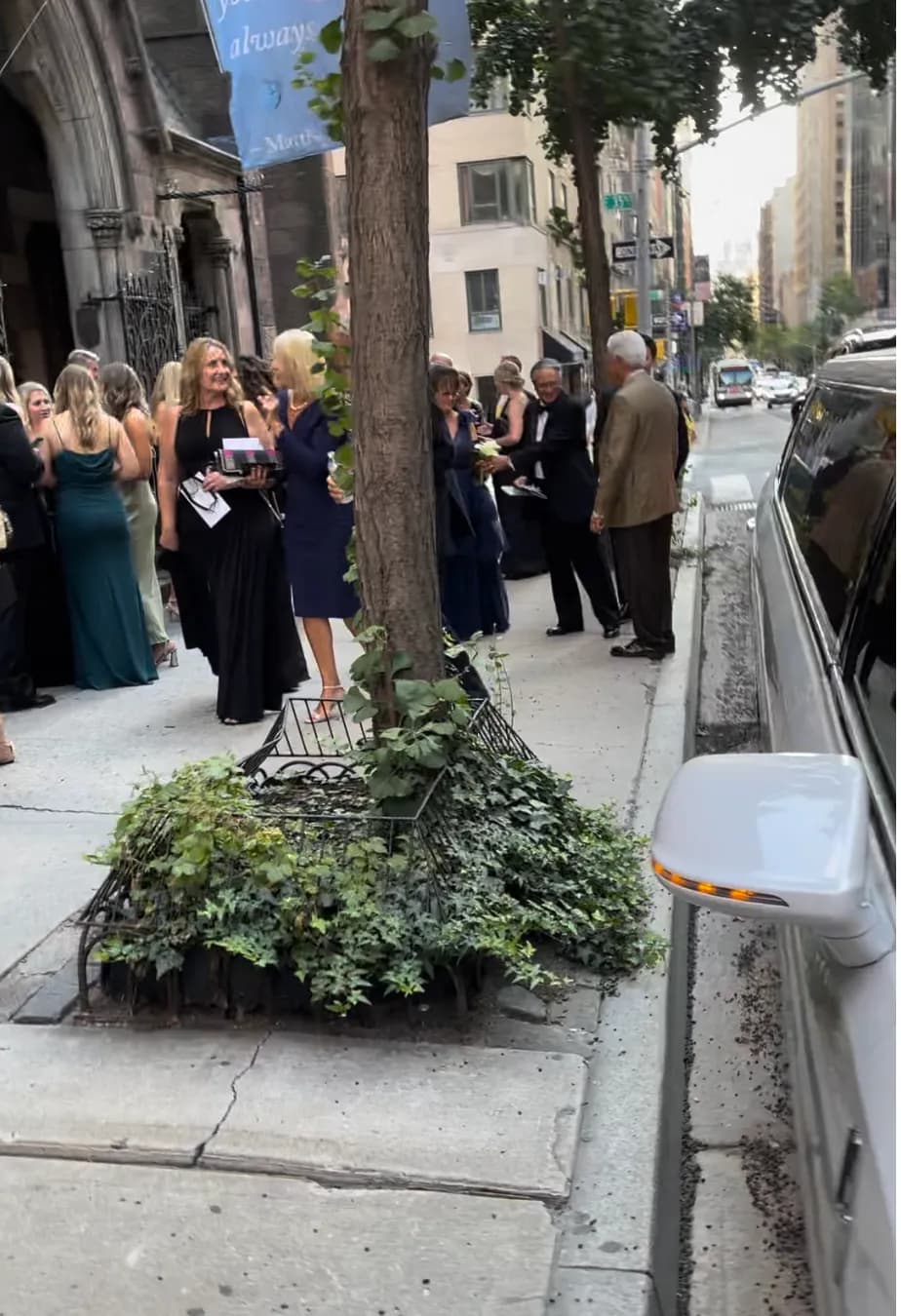 Wedding guests chatting outside the church beside the white limousine